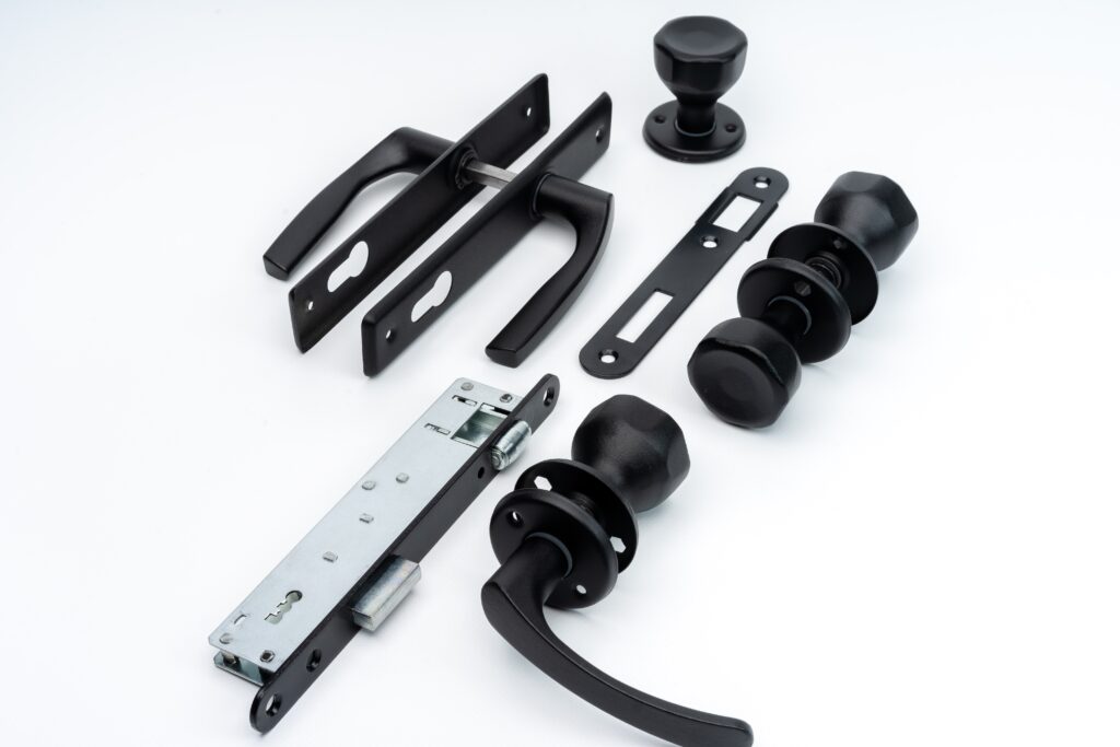 czarny zestaw okuć drzwiowych z klamkami, gałkami i zamkiem na białym tle